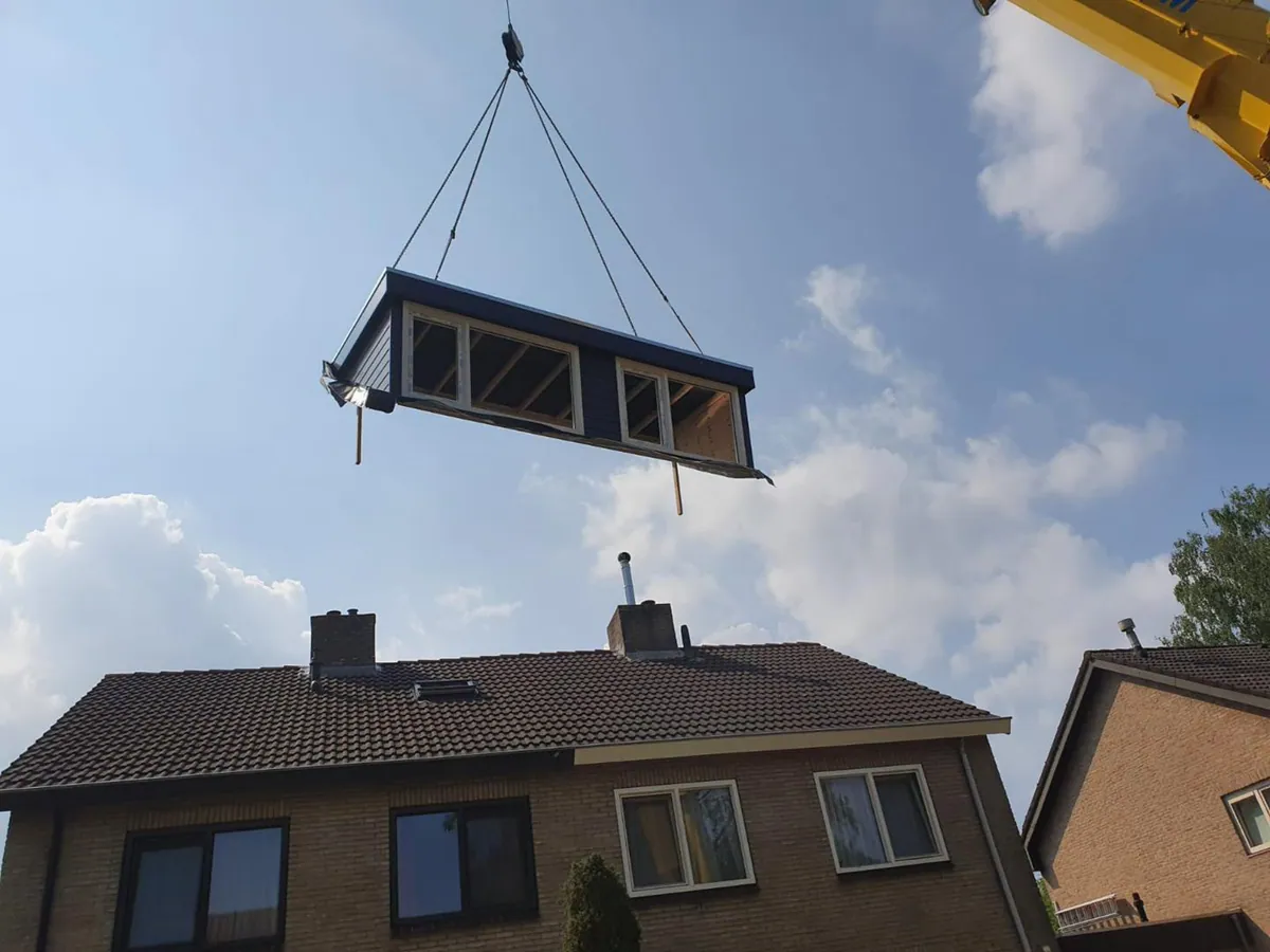 Een nieuwe dakkapel wordt met een kraan op het dak gehesen bij een project in Zwolle